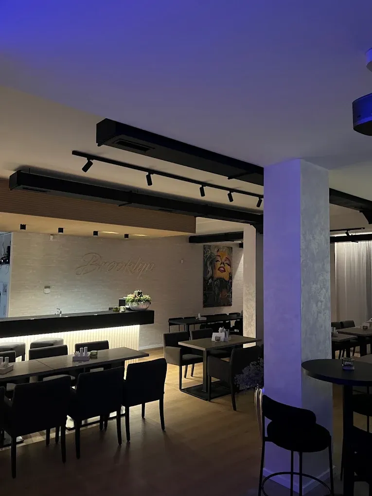 Reštaurácia zvnútra: stoly, bar a nápis Brooklyn na stene